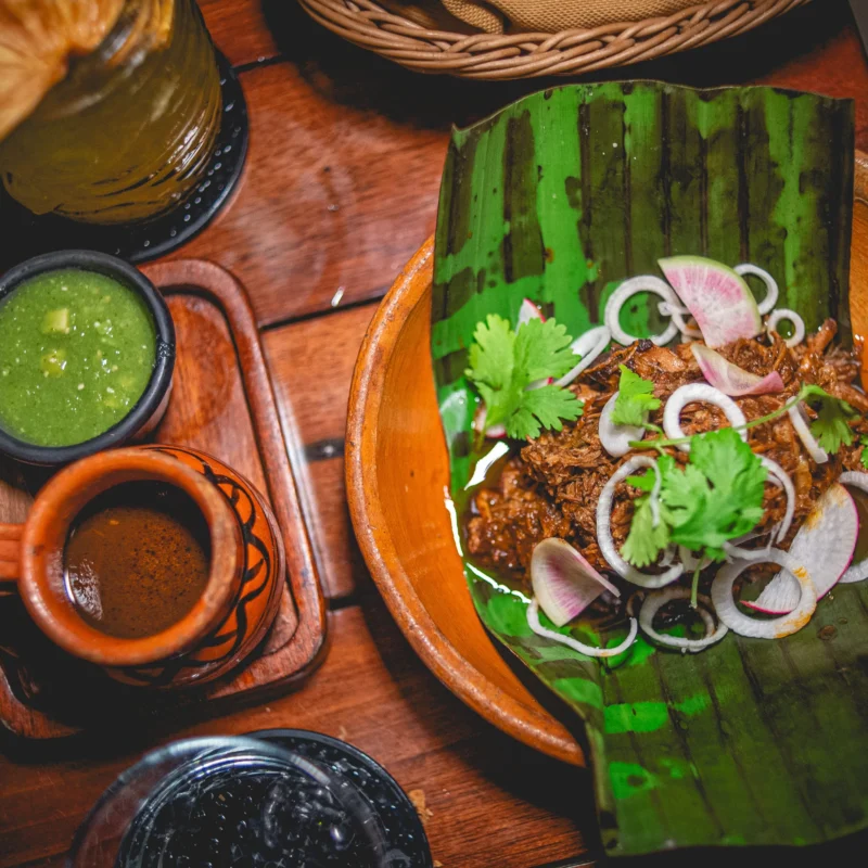 barbacoa de res Beef brisket in Mexican barbecue sauce, corn tortillas, beef consommé, tomatillo sauce served on a banana leaf at Ziggy restaurant in Tulum