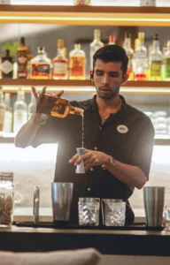 barman measuring tequila in a tumbler