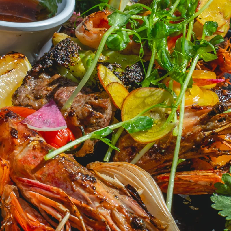 garlic shrimp a plate of Jumbo shrimp with garlic sauce, mixed greens, avocado, cherry tomatoes, parsley, coriander, roasted yellow lime, sweet potato chips and garlic aioli.