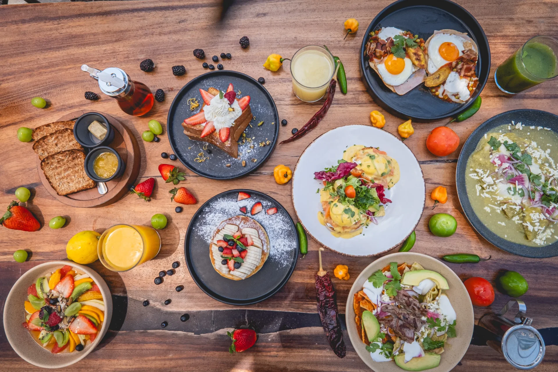 a table of breakfast options at Ziggy Restaurant with eggs benedict, freshly baked bread, fruit salad, pancakes, 