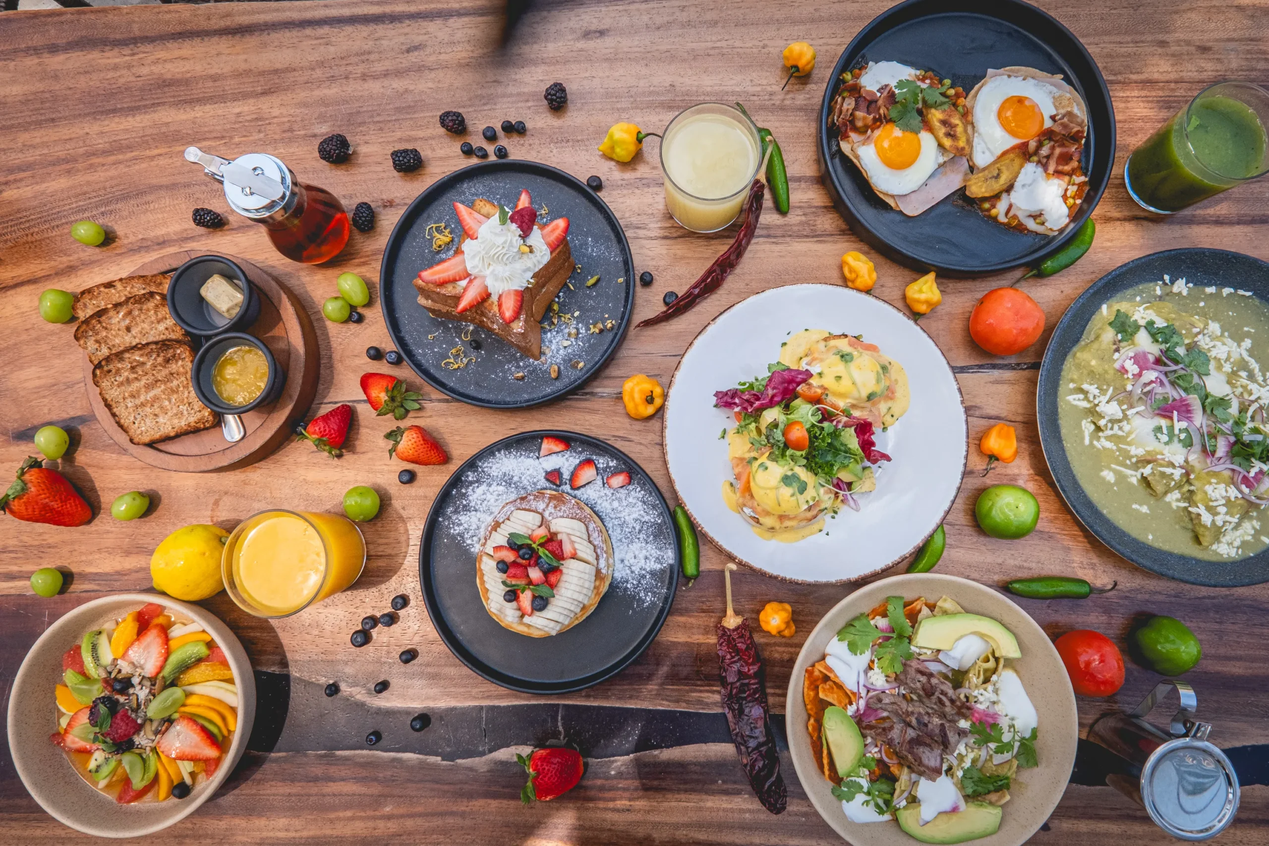 a table of breakfast options at Ziggy Restaurant with eggs benedict, freshly baked bread, fruit salad, pancakes,